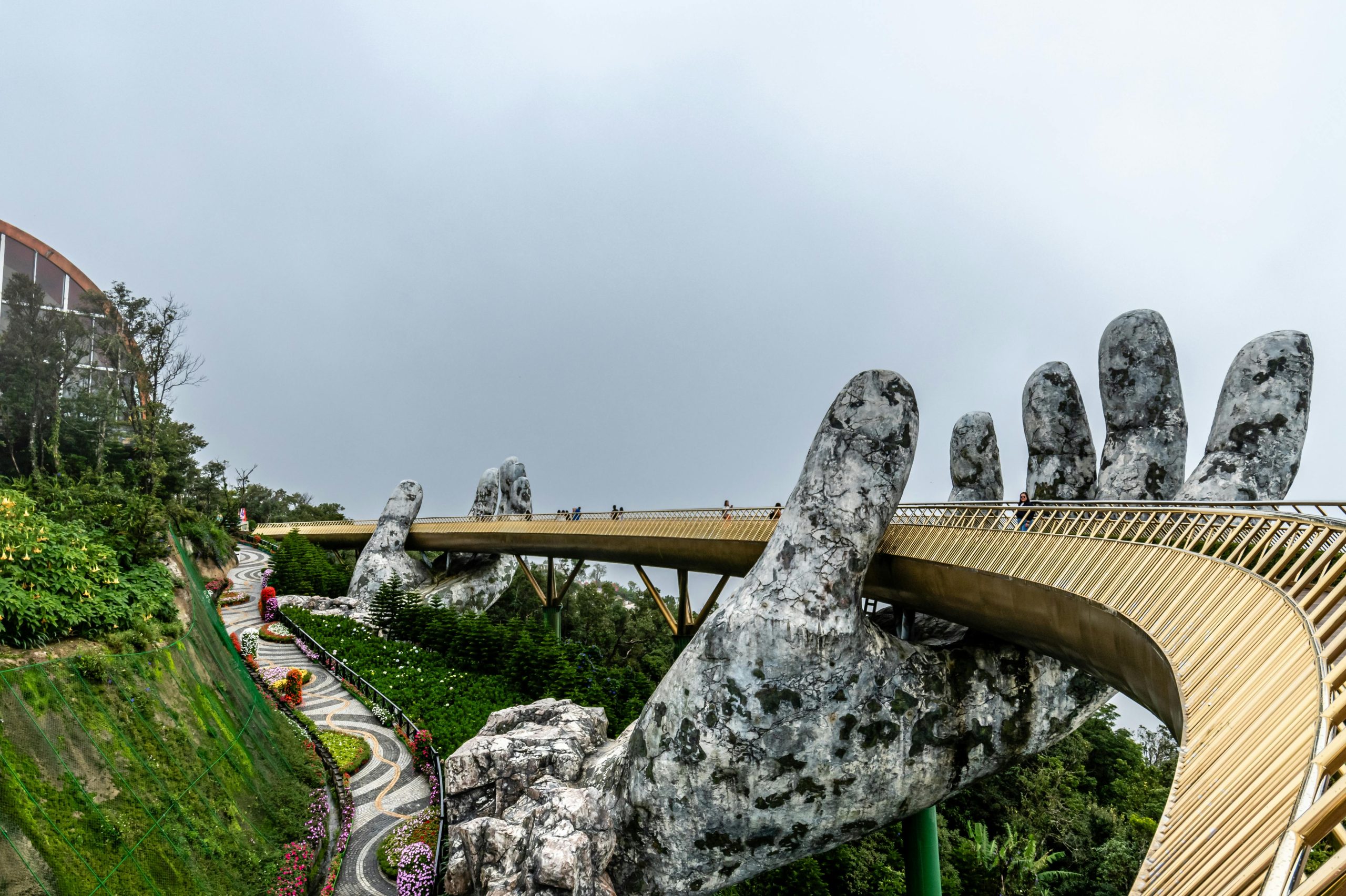 Explore the iconic Golden Bridge in Da Nang, Vietnam, held by giant stone hands amidst lush greenery.